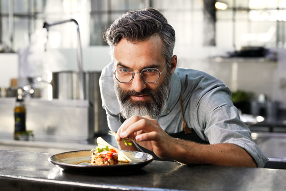 Mann mit Varilux Gleitsichtgläsern von Essilor beim Kochen und Essenzubereiten